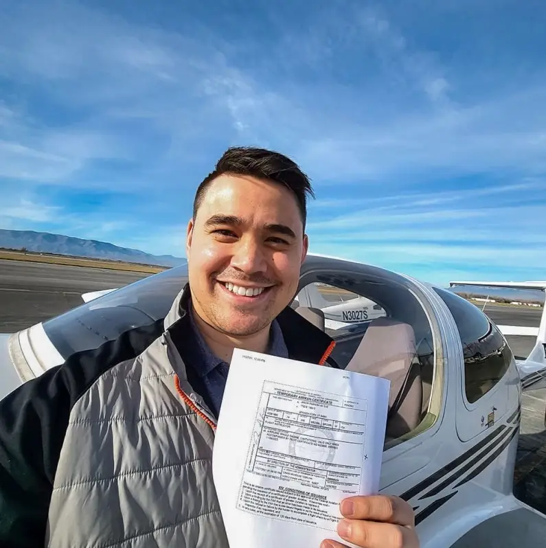 Student posing next to aircraft with certificate