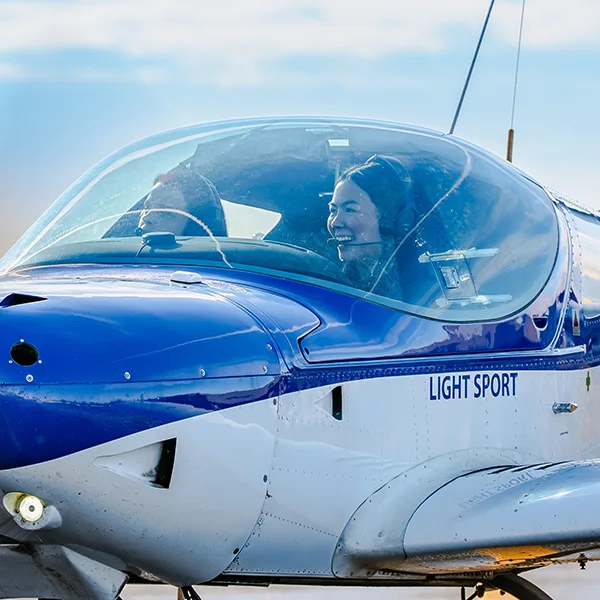 A woman smiles in the cockpit during flight training