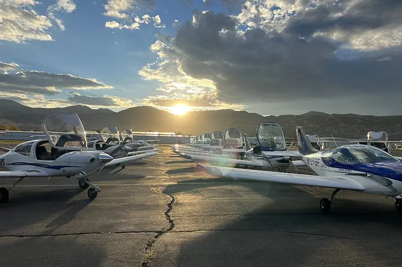 Small aircraft on the tarmac with a setting sun in the background.