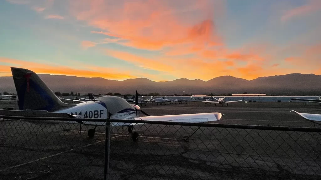 Small aircraft on the tarmac, facing a sunset.