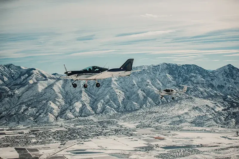 small aircraft at sunrise over snowy mountains.